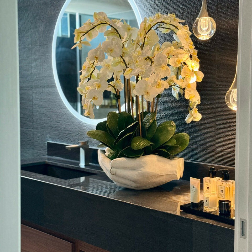 Weiße Phalaenopsis-Orchideen in Vase mit Skulptur „Offene Hände“